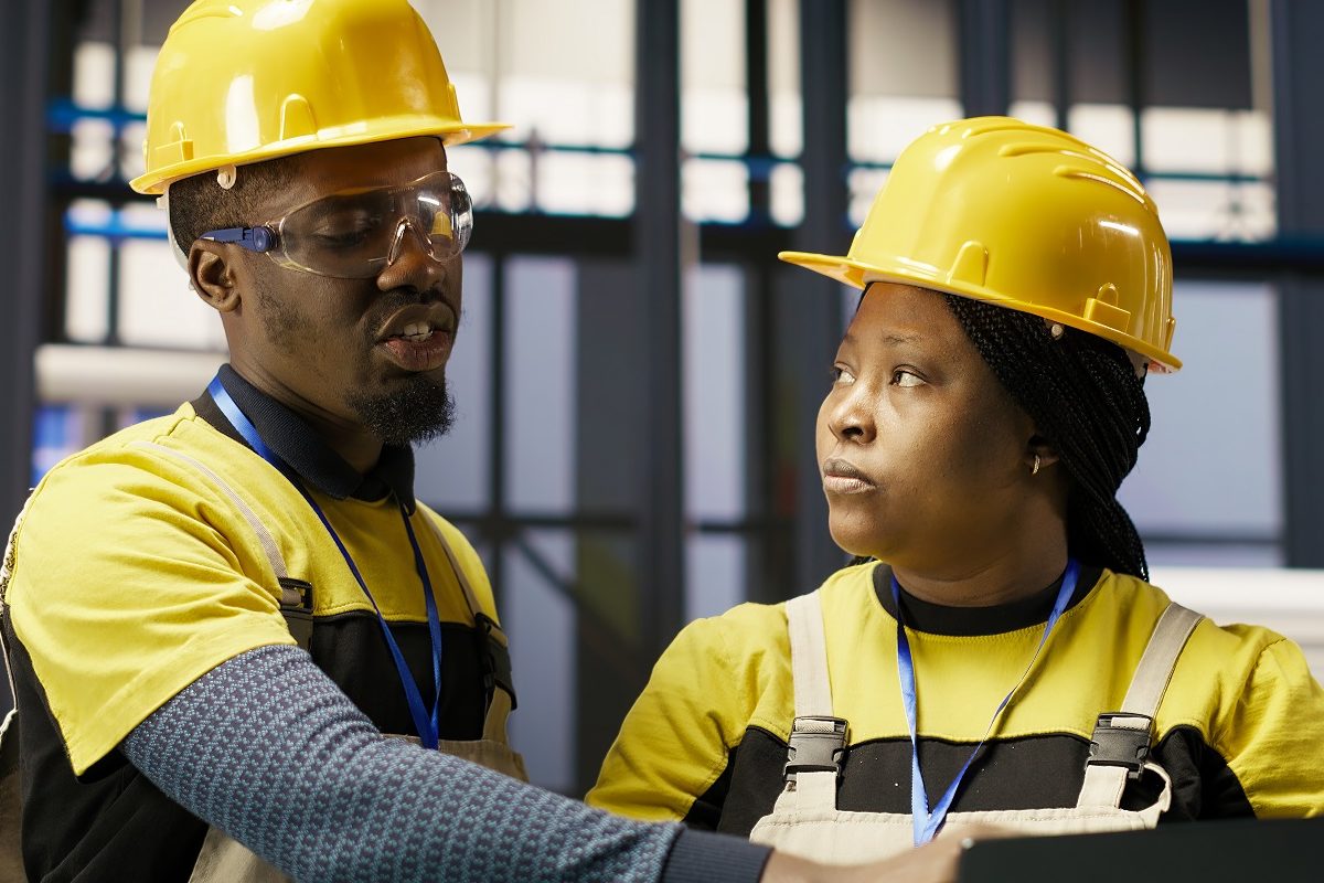 Solar panels factory team working together to fix gear, following maintenance procedures. Photovoltaics plant coworkers doing brainstorming, analyzes data on laptop to predict failures, camera B